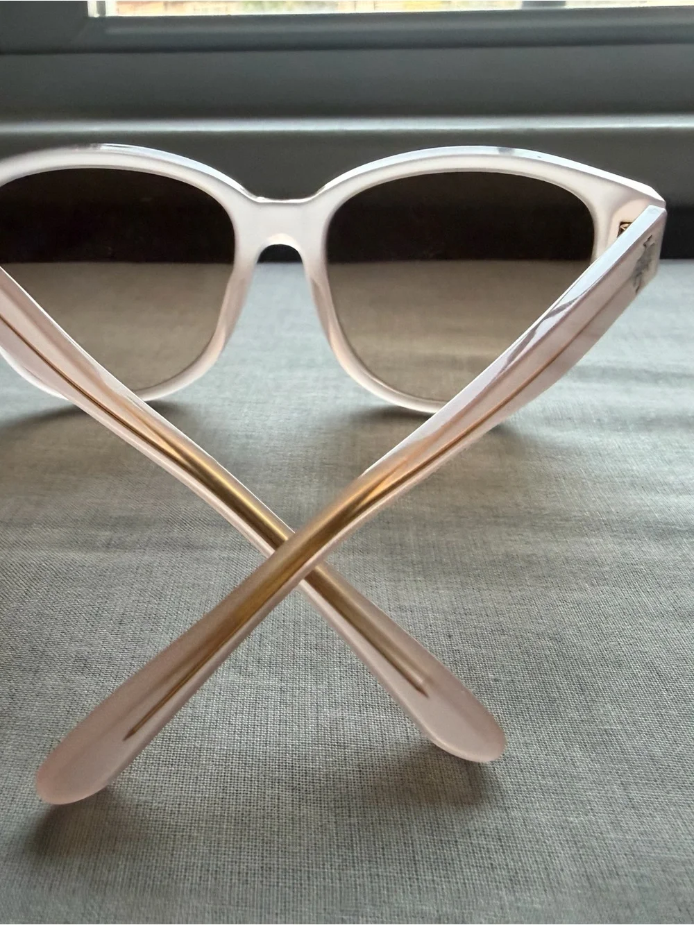 Tory Burch Pale Pink Frame Sunglasses with cat eye shape with gold detail.